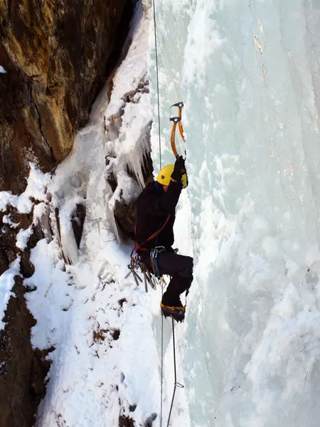 Man climbing frozen waterfall Stock Photo