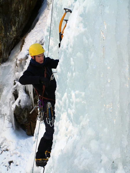 Man climbing frozen waterfall Stock Image