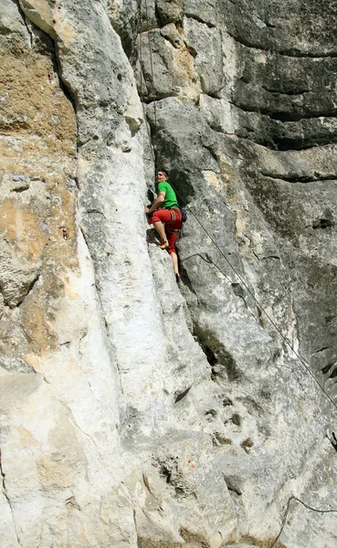 Jovem escalando parede vertical com vista para o vale no fundo — Fotografia de Stock