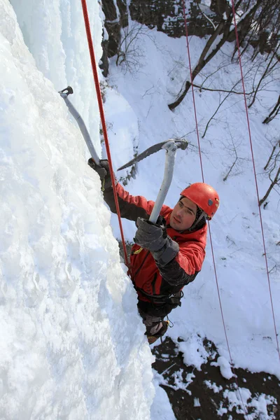Man climbing frozen waterfall Stock Picture