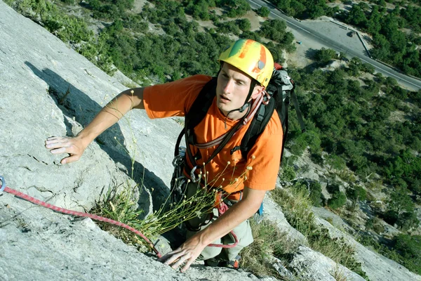 Młody człowiek pionowa ściana wspinaczkowa z widokiem na dolinę na tle — Zdjęcie stockowe