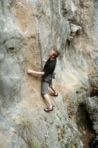 Молодий чоловік сходження вертикальною стіною з видом на долину на фоні — стокове фото