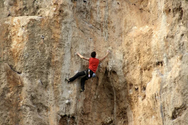 Jovem escalando parede vertical com vista para o vale no fundo — Fotografia de Stock