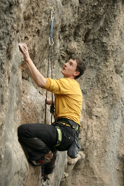 Jovem escalando parede vertical com vista para o vale no fundo — Fotografia de Stock