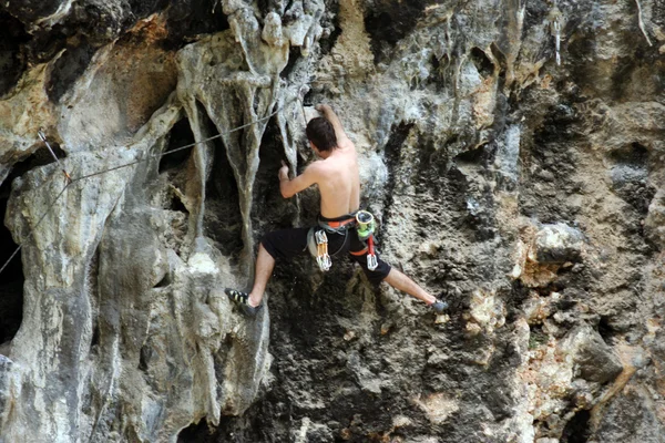 Young man climbing vertical wall with valley view on the background — Stock Photo, Image