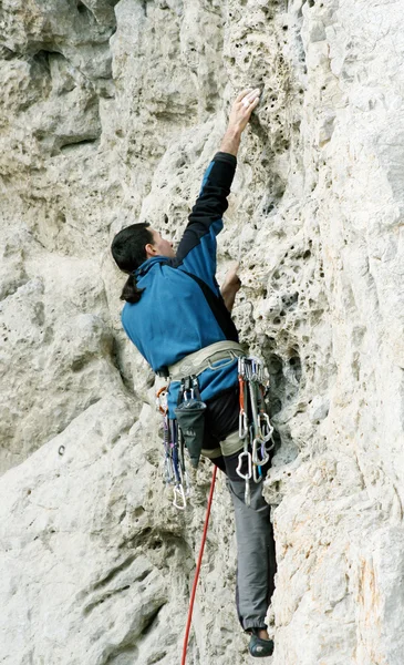 Hombre joven escalando pared vertical con vista al valle en el fondo —  Fotos de Stock