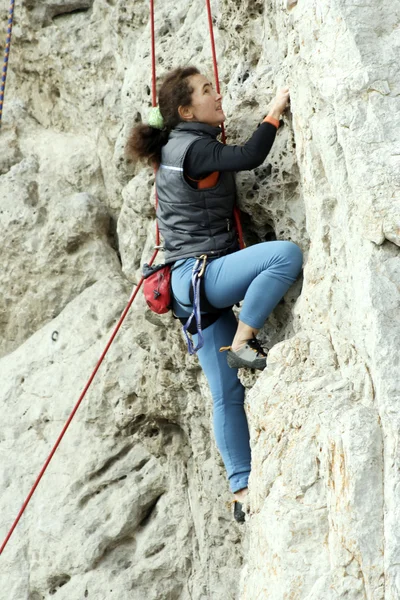 Junger Mann klettert senkrechte Wand mit Talblick im Hintergrund — Stockfoto