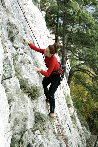 Молодий чоловік сходження вертикальною стіною з видом на долину на фоні — стокове фото