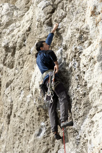 Молодой человек лазает по вертикальной стене с видом на долину на заднем плане — стоковое фото