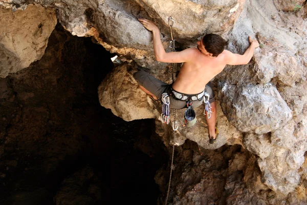 Jovem escalando parede vertical com vista para o vale no fundo — Fotografia de Stock