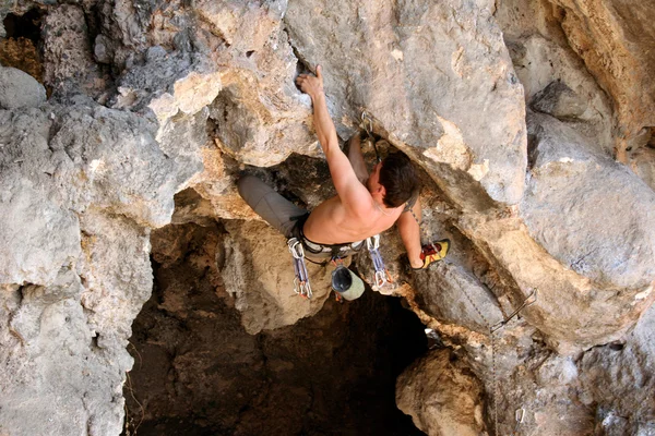 若い男が渓谷の景色を背景に垂直の壁を登る — ストック写真