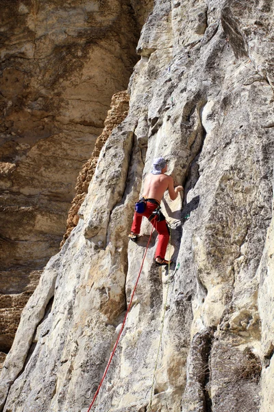 Giovane arrampicata su una parete calcarea con ampia valle sullo sfondo — Foto Stock