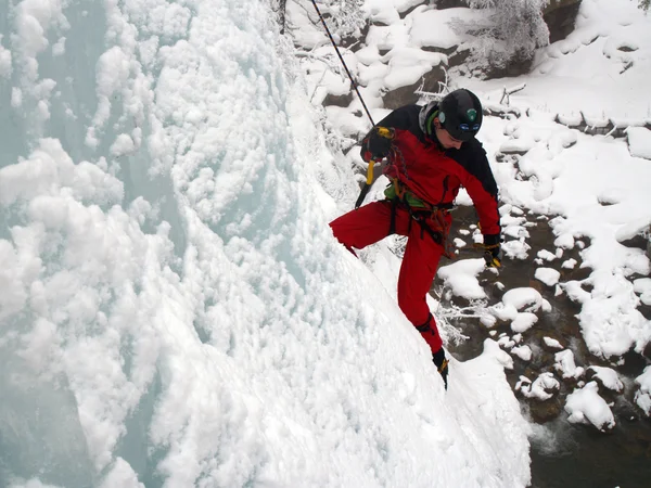 Scalatore di ghiaccio lotta su una cascata ghiacciata . — Foto Stock