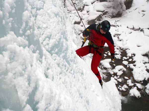 Ice climber strijd omhoog een bevroren waterval. — Stockfoto