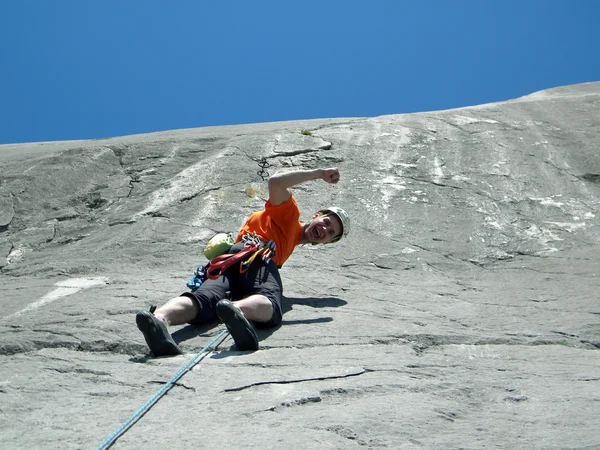 Junger Mann klettert an einer Kalksteinwand mit breitem Tal im Hintergrund — Stockfoto