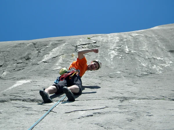 Joven escalando en una pared de piedra caliza con amplio valle en el fondo — Foto de Stock