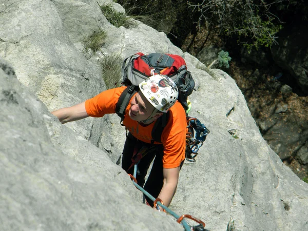 Joven escalando en una pared de piedra caliza con amplio valle en el fondo —  Fotos de Stock