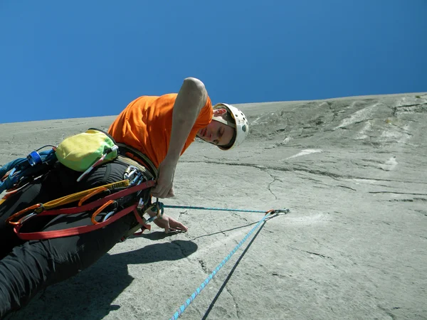 Jovem escalando em uma parede de pedra calcária com amplo vale no fundo — Fotografia de Stock