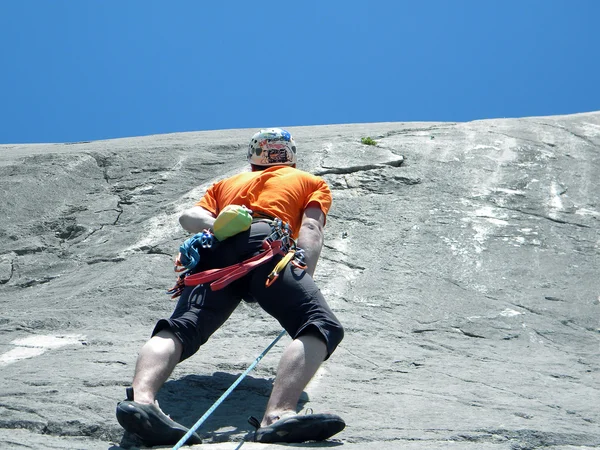 Jovem escalando em uma parede de pedra calcária com amplo vale no fundo — Fotografia de Stock