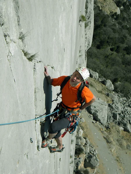 Joven escalando en una pared de piedra caliza con amplio valle en el fondo —  Fotos de Stock