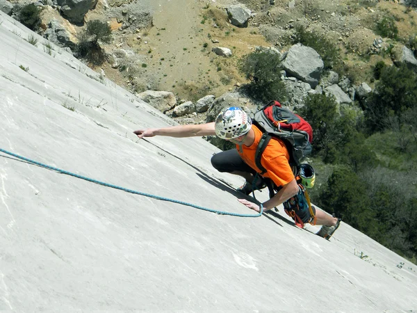 Joven escalando en una pared de piedra caliza con amplio valle en el fondo — Foto de Stock