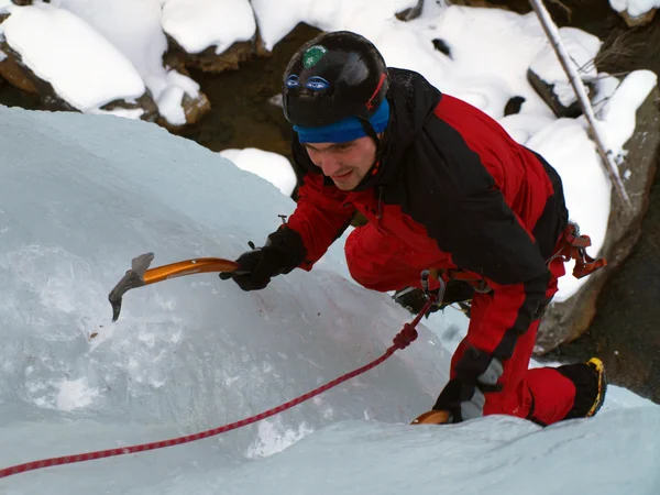 Man climbing frozen waterfall Stock Image