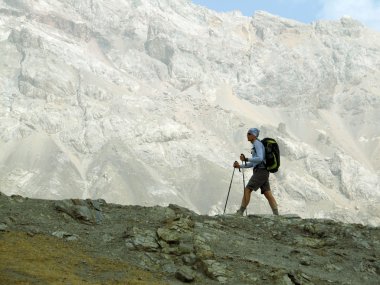 Sırt çantalı yürüyüşçüler dağın tepesinden vadi manzarasının keyfini çıkarıyorlar.