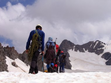 Sırt çantalı yürüyüşçüler dağın tepesinden vadi manzarasının keyfini çıkarıyorlar.