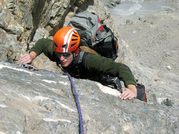 Young man climbing on a limestone wall with wide valley on the background — Stock Photo, Image