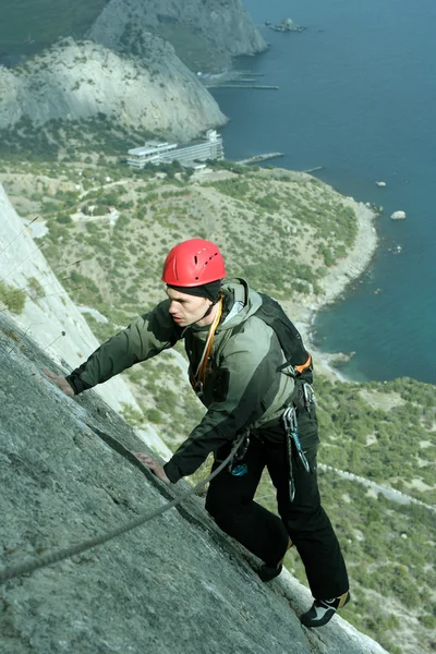 Joven escalando en una pared de piedra caliza con amplio valle en el fondo — Foto de Stock