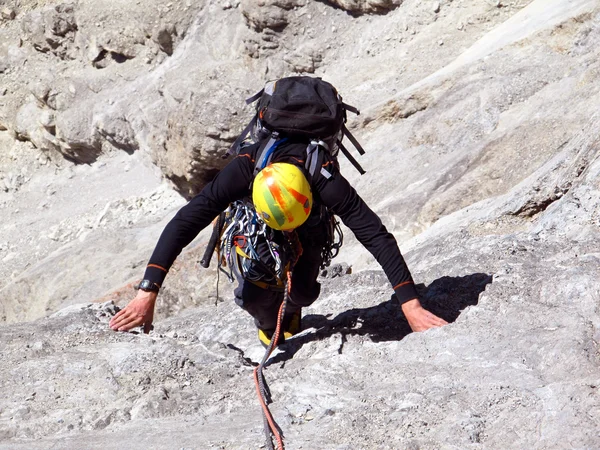 Joven escalando en una pared de piedra caliza con amplio valle en el fondo — Foto de Stock