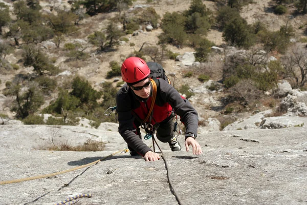 Joven escalando en una pared de piedra caliza con amplio valle en el fondo —  Fotos de Stock