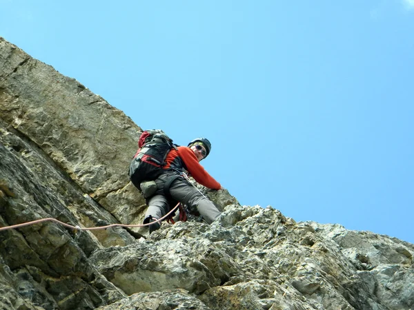 Junger Mann klettert an einer Kalksteinwand mit breitem Tal im Hintergrund — Stockfoto