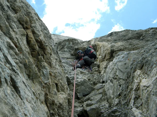 Joven escalando en una pared de piedra caliza con amplio valle en el fondo — Foto de Stock