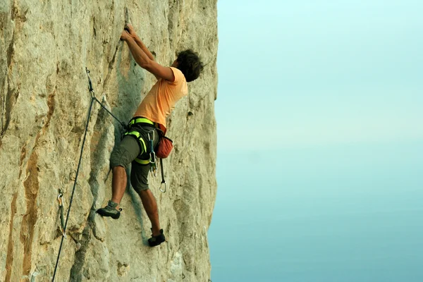 Joven escalando en una pared de piedra caliza con amplio valle en el fondo — Foto de Stock