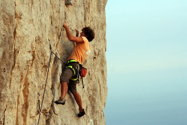 Young man climbing on a limestone wall with wide valley on the background — Stock Photo, Image