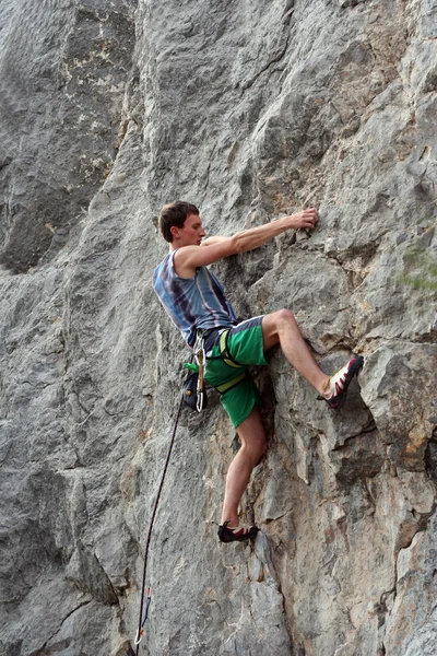 Jovem escalando em uma parede de pedra calcária com amplo vale no fundo — Fotografia de Stock