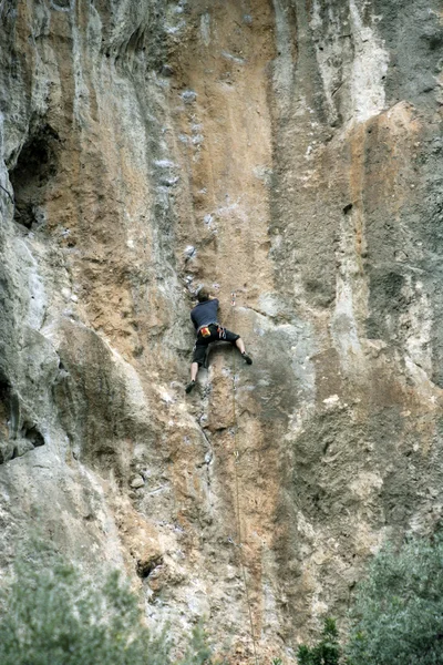 Junger Mann klettert an einer Kalksteinwand mit breitem Tal im Hintergrund — Stockfoto