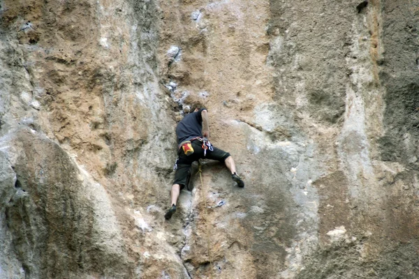 Giovane arrampicata su una parete calcarea con ampia valle sullo sfondo — Foto Stock