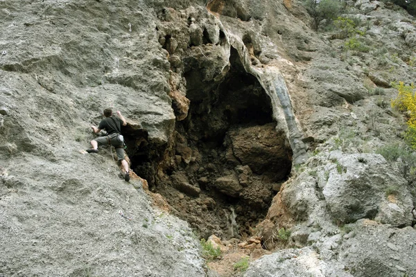 Νεαρός σκαρφαλώνει σε ασβεστολιθικό τοίχο με μεγάλη κοιλάδα στο βάθος — Φωτογραφία Αρχείου