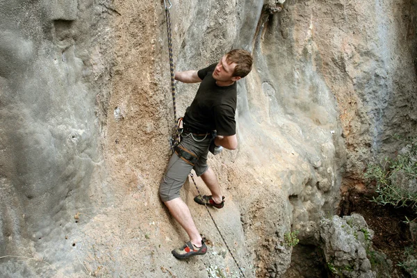 Joven escalando en una pared de piedra caliza con amplio valle en el fondo —  Fotos de Stock