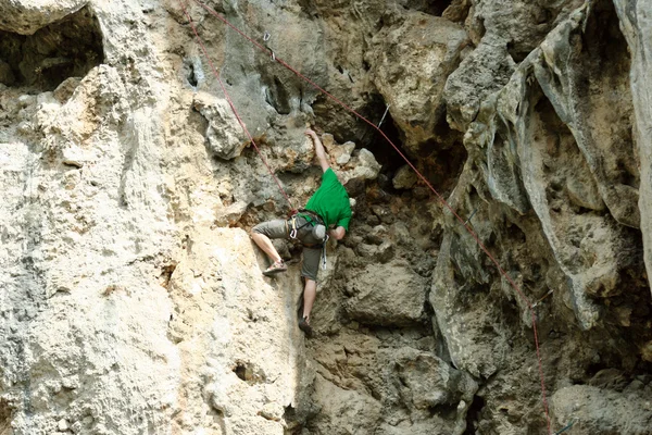 Jovem escalando parede vertical com vista para o vale no fundo — Fotografia de Stock