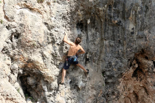 Jeune homme grimpant sur un mur de calcaire avec une large vallée sur le fond — Photo