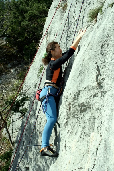Jovem mulher escalando parede vertical com vista para o vale no fundo — Fotografia de Stock