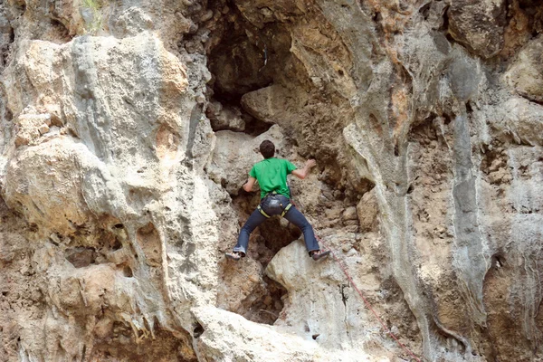 Jovem escalando parede vertical com vista para o vale no fundo — Fotografia de Stock