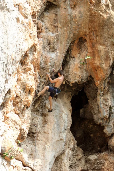 Jeune homme grimpant sur un mur de calcaire avec une large vallée sur le fond — Photo