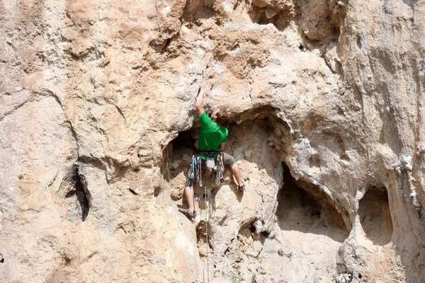 Young man climbing vertical wall with valley view on the background — Stock Photo, Image