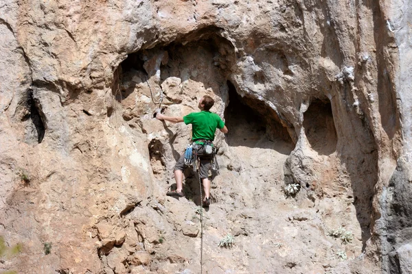 Young man climbing vertical wall with valley view on the background — Stock Photo, Image