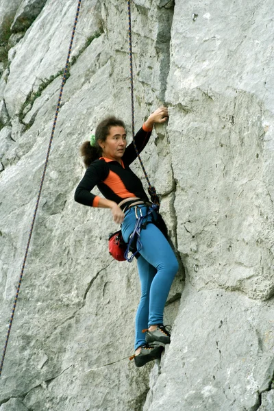 Junge Frau klettert senkrechte Wand mit Talblick im Hintergrund — Stockfoto