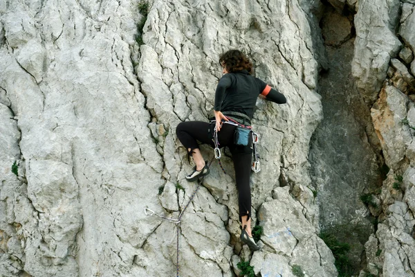 Молода жінка піднімається на вапнякову стіну з широкою долиною на фоні — стокове фото